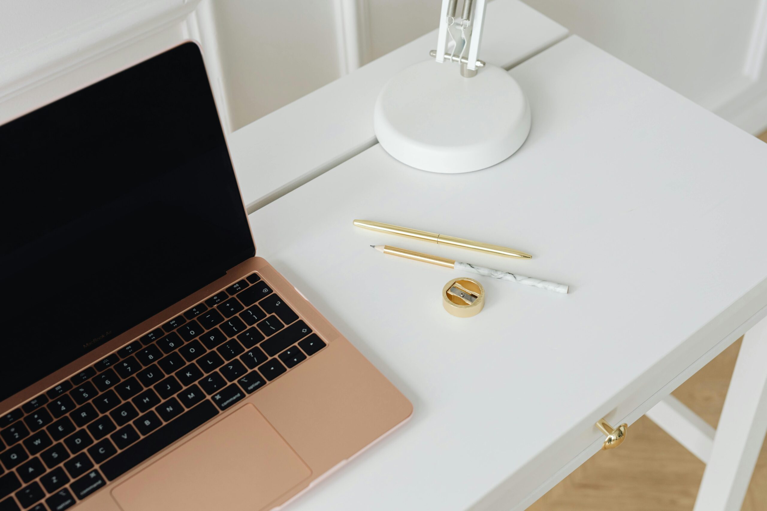 A clean, minimalist desk setup with a laptop, pens, and lamp, perfect for workspaces.